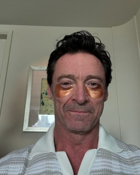 the actor Hugh Jackman in a selfie, wearing gold irridescent eye patches under his eyes and smiling