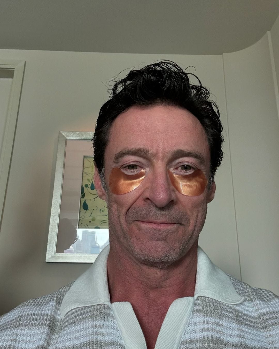 the actor Hugh Jackman in a selfie, wearing gold irridescent eye patches under his eyes and smiling