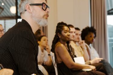 Attendees sit listening, seated in rows.