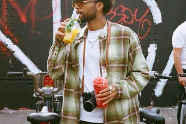 man drinking a fruit juice and holding a cup of diced watermelon