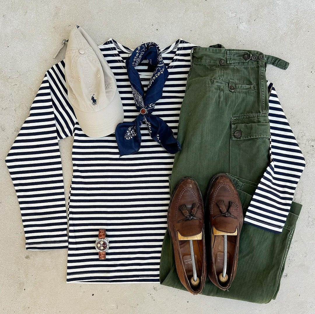 flat lay of a casual men's outfit featuring a blue and white striped long-sleeve shirt, blue bandana, off-white baseball cap, green pants, and brown tassel loafers