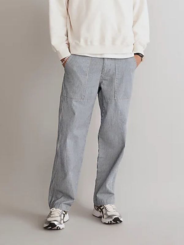 man from the waist down wearing train conductor stripe baggy pants with a cream-colored sweatshirt