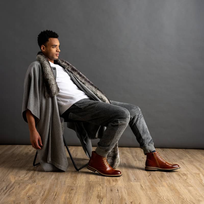 man sitting on a chair wearing a pair of brown wingtip boots by Bruno Marc