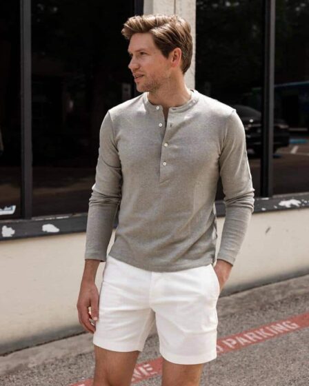 man wearing a long sleeved grey henley shirt and white shorts