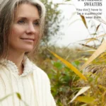 Mature woman wearing sweater outside near yellow and green foliage.