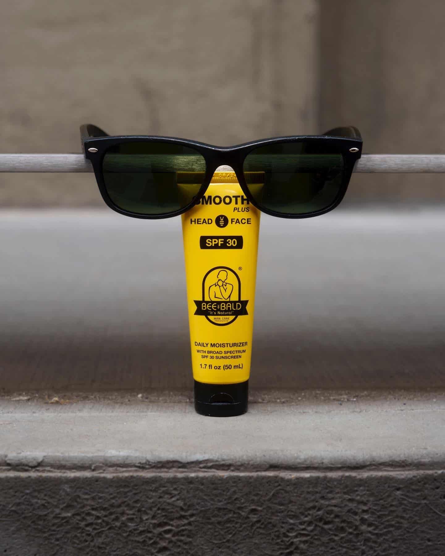 a tube of bee bald daily moisturizer with sunglasses