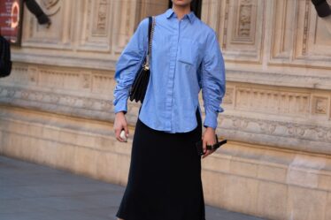 LONDON ENGLAND  SEPTEMBER 15 Model Ling Chen wears Airpods a blue blouse black skirt and light pink jelly sandals after...