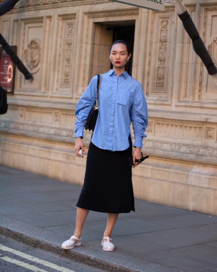 LONDON ENGLAND  SEPTEMBER 15 Model Ling Chen wears Airpods a blue blouse black skirt and light pink jelly sandals after...