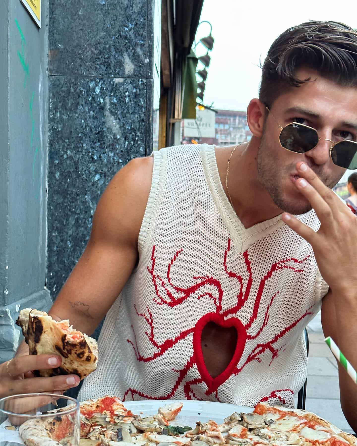 man with sunglasses eating a slice of pizza