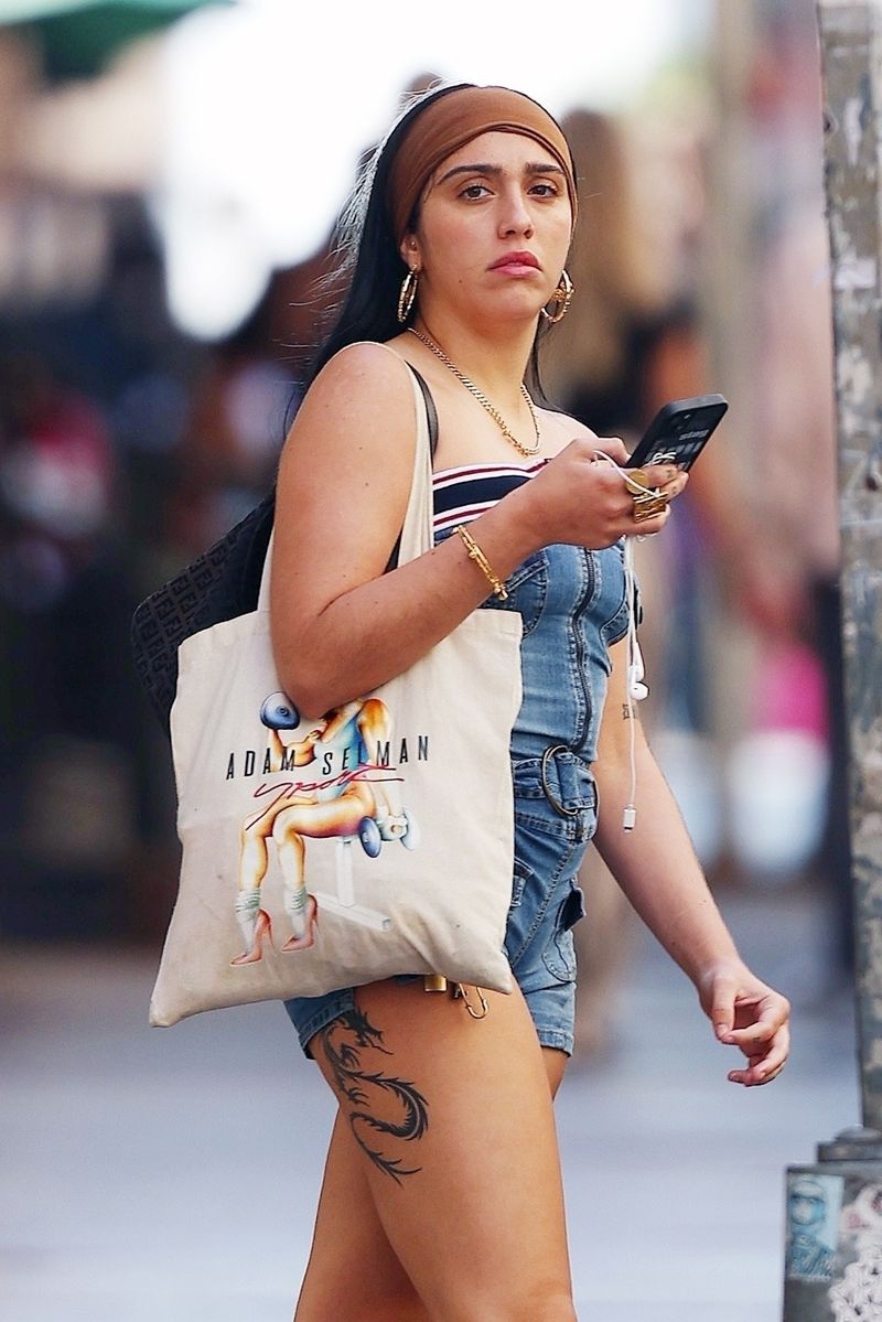 Lourdes Leon turns heads in Tribeca, wearing a trendy denim playsuit with a strapless striped bandeau top, accessorized with a Fendi bag, gold hoop earrings, and white high-top sneakers.