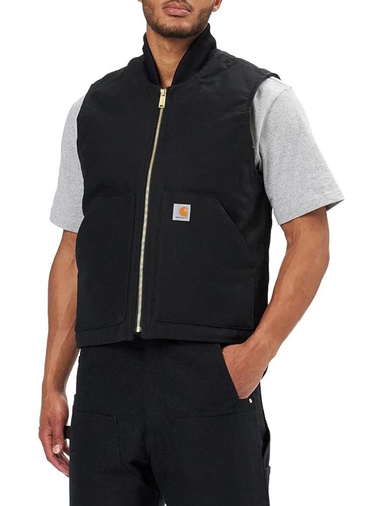 man from the neck down wearing a black carhartt wip sleeveless vest over a grey t-shirt