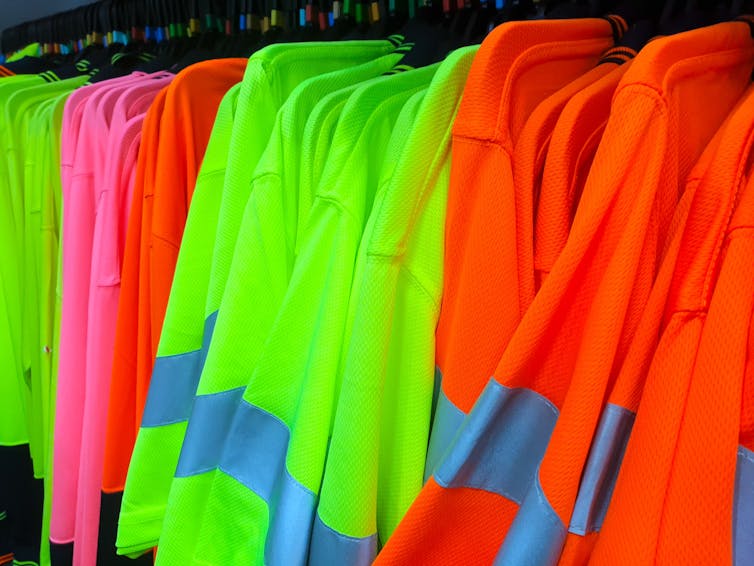 hi-vis shirts on a rack, yellow, pink and orange with retro-reflective strips