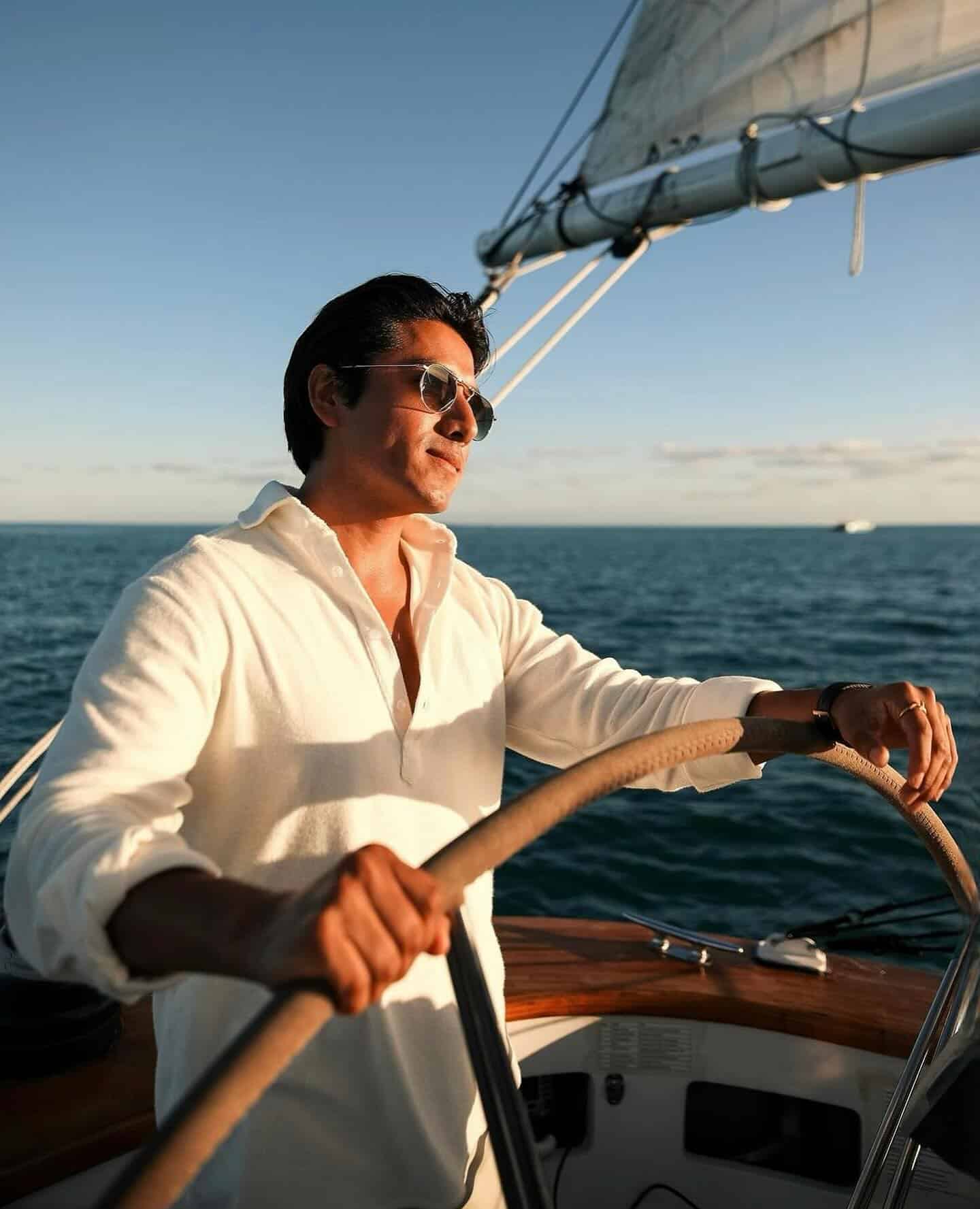 man with sunglasses navigating a yatch