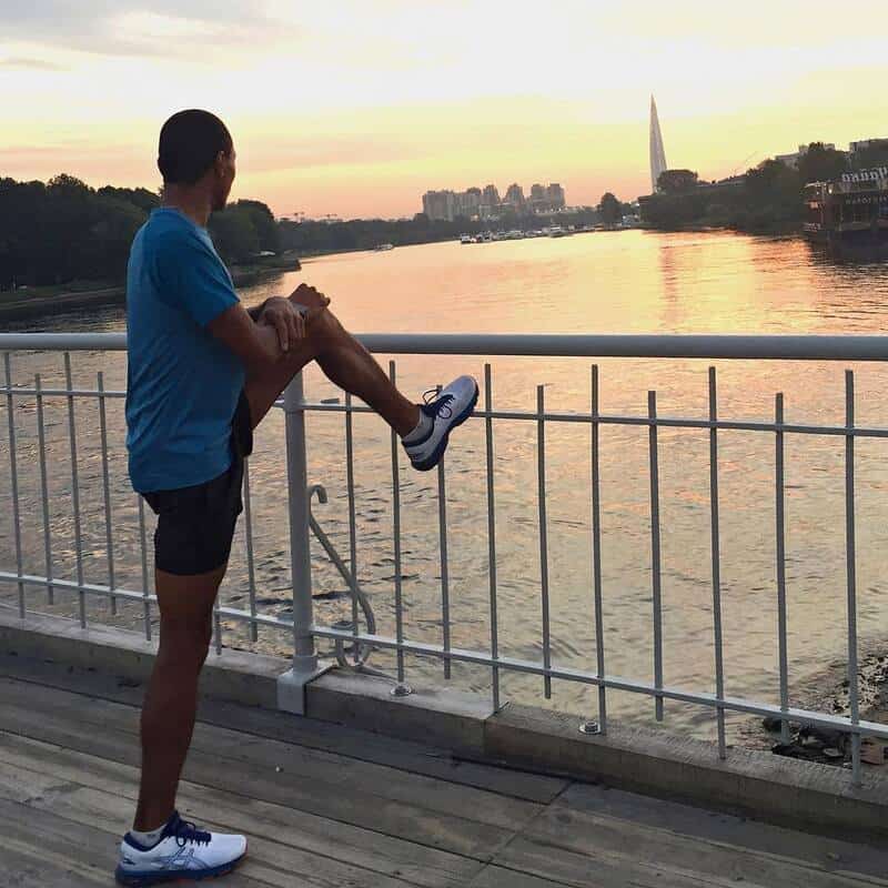 man wearing a pair of asics shoes while stretching