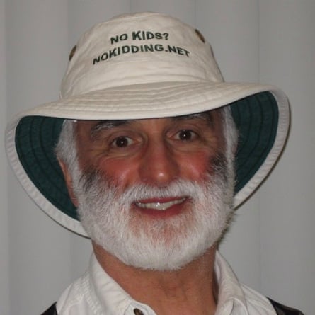 A man wearing a bucket hat. There is text embroidered on it which reads ‘No Kids? Nokidding.net’