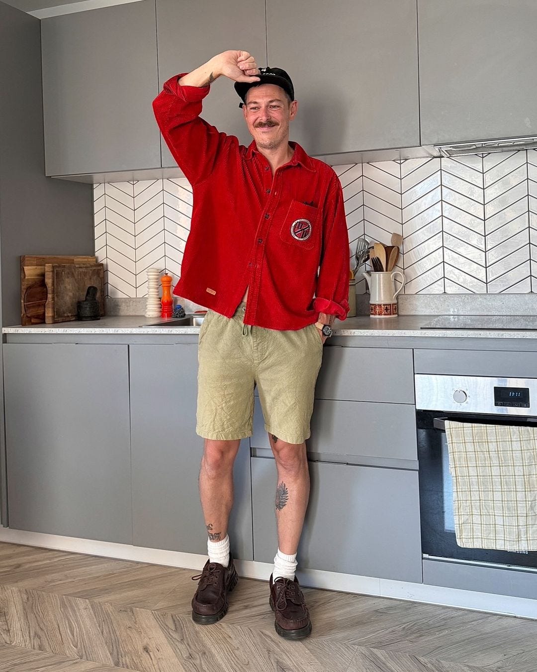 man in a red button-up shirt, khaki shorts, and brown shoes with white socks