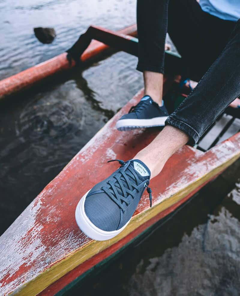 man in a small boat wearing the Cala sneakers by Tropicfeel