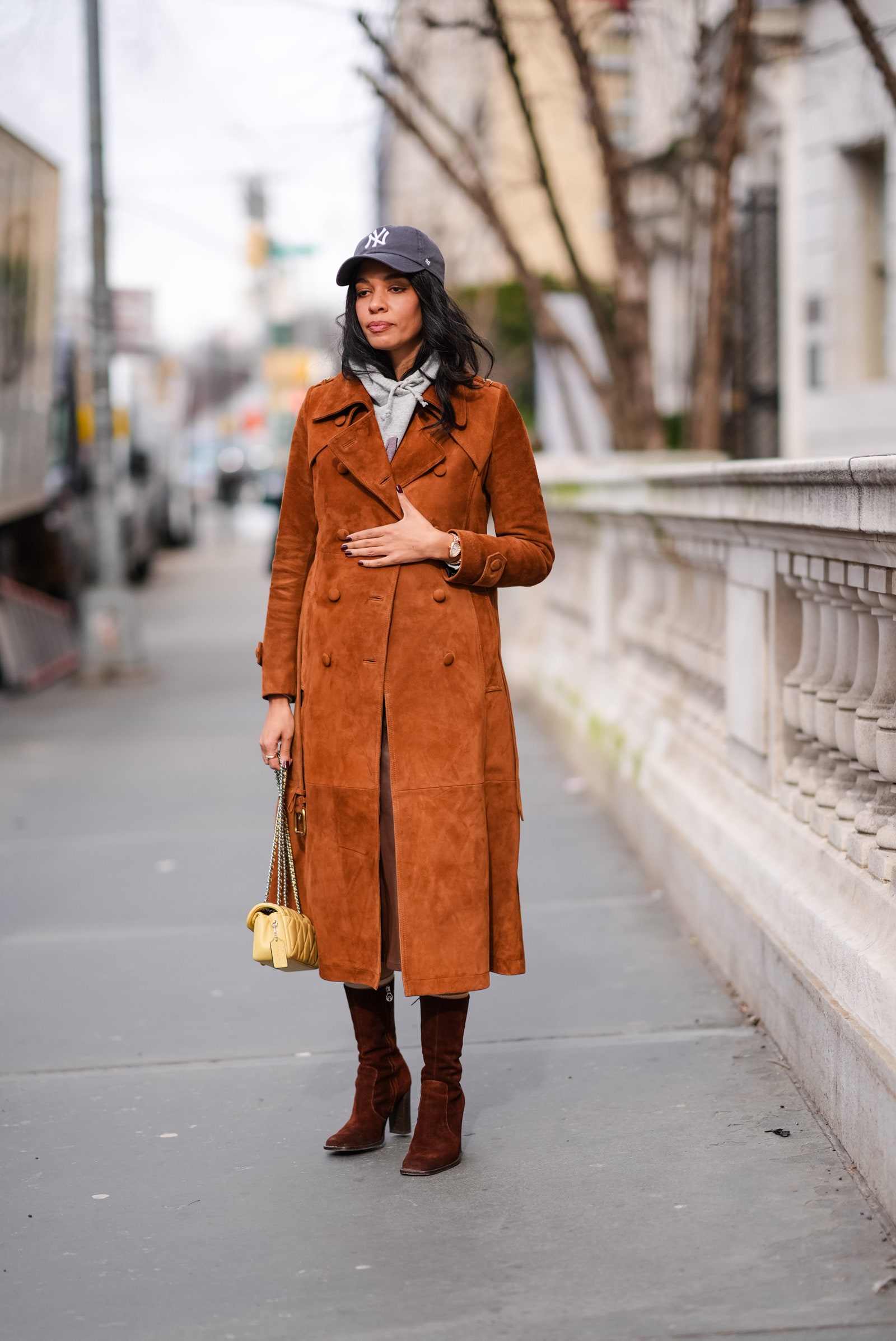 NEW YORK NEW YORK  FEBRUARY 12 A guest wears a NY cap hat a gray hoodie sweater  a brown  orange suede trench long coat ...