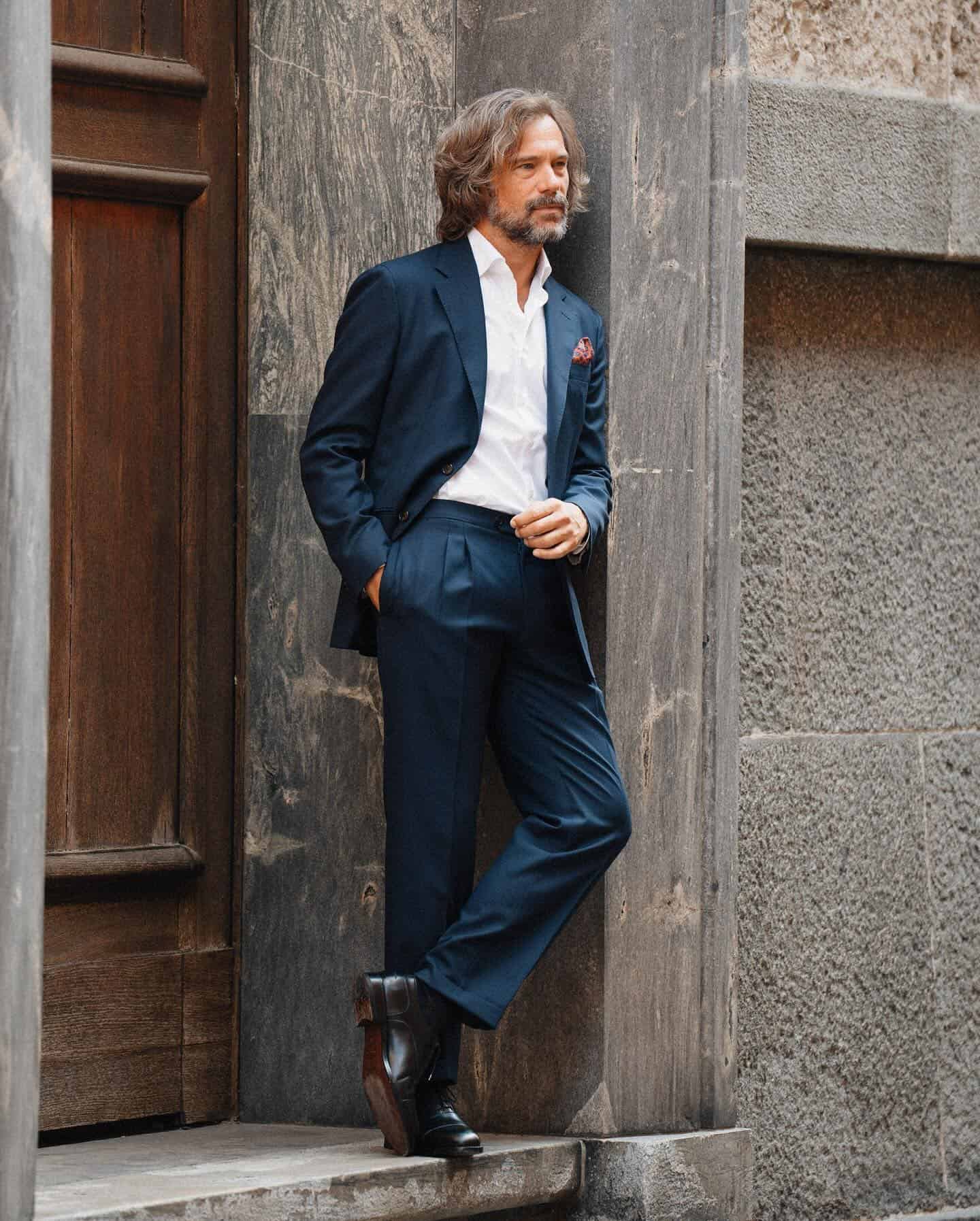 man in a navy suit standing by the doorway