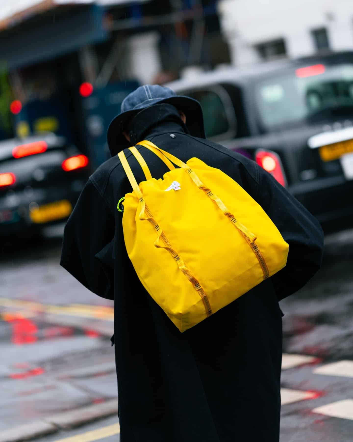 man in a black coat carrying a yellow tote bag