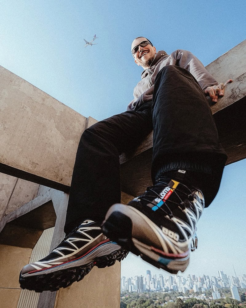 man sitting on top of a concrete structure wearing a pair of Salomon X-Ultra