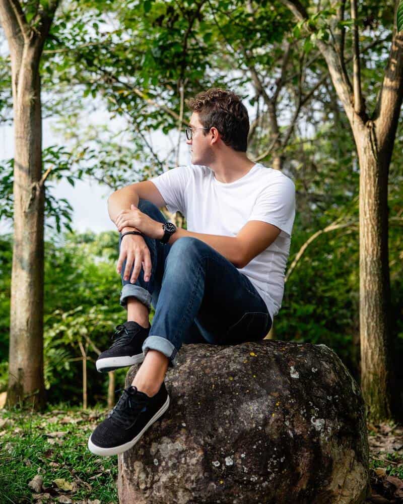 man sitting on a large rock wearing a pair of Weekend Sneakers with white sole by Vessi