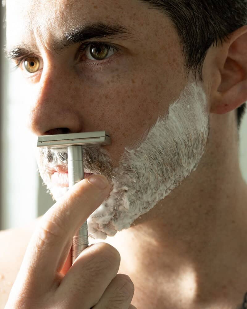 man shaving his mustache covered with shaving cream