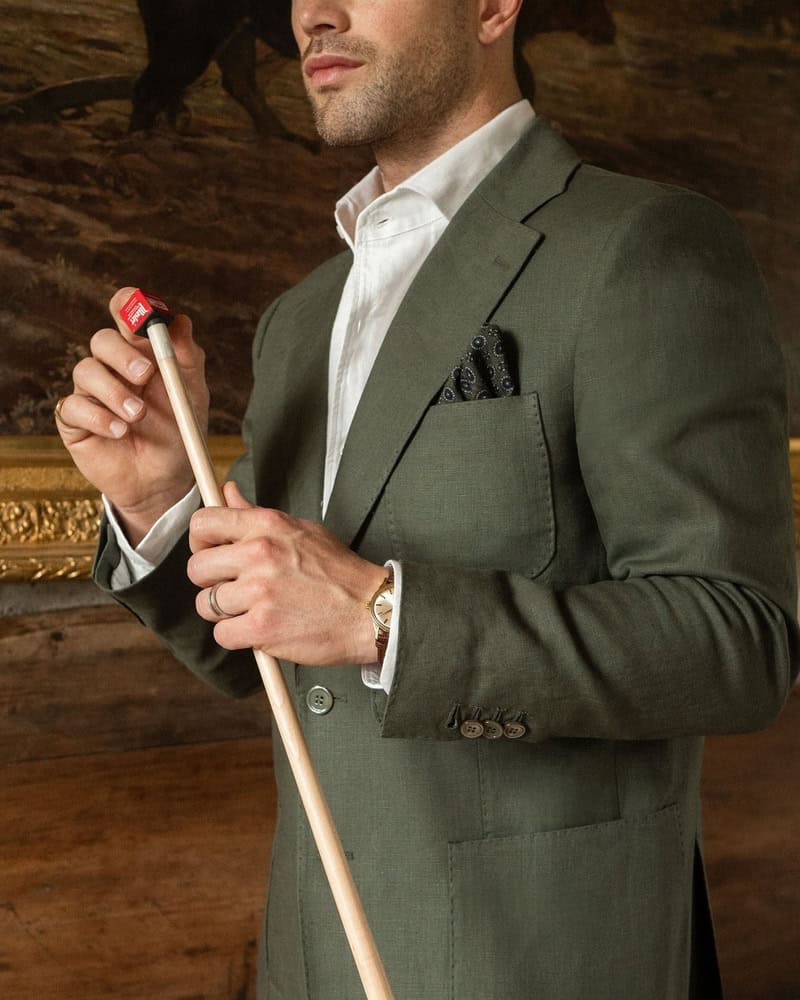 man in a linen suit applying chalk to a cue stick