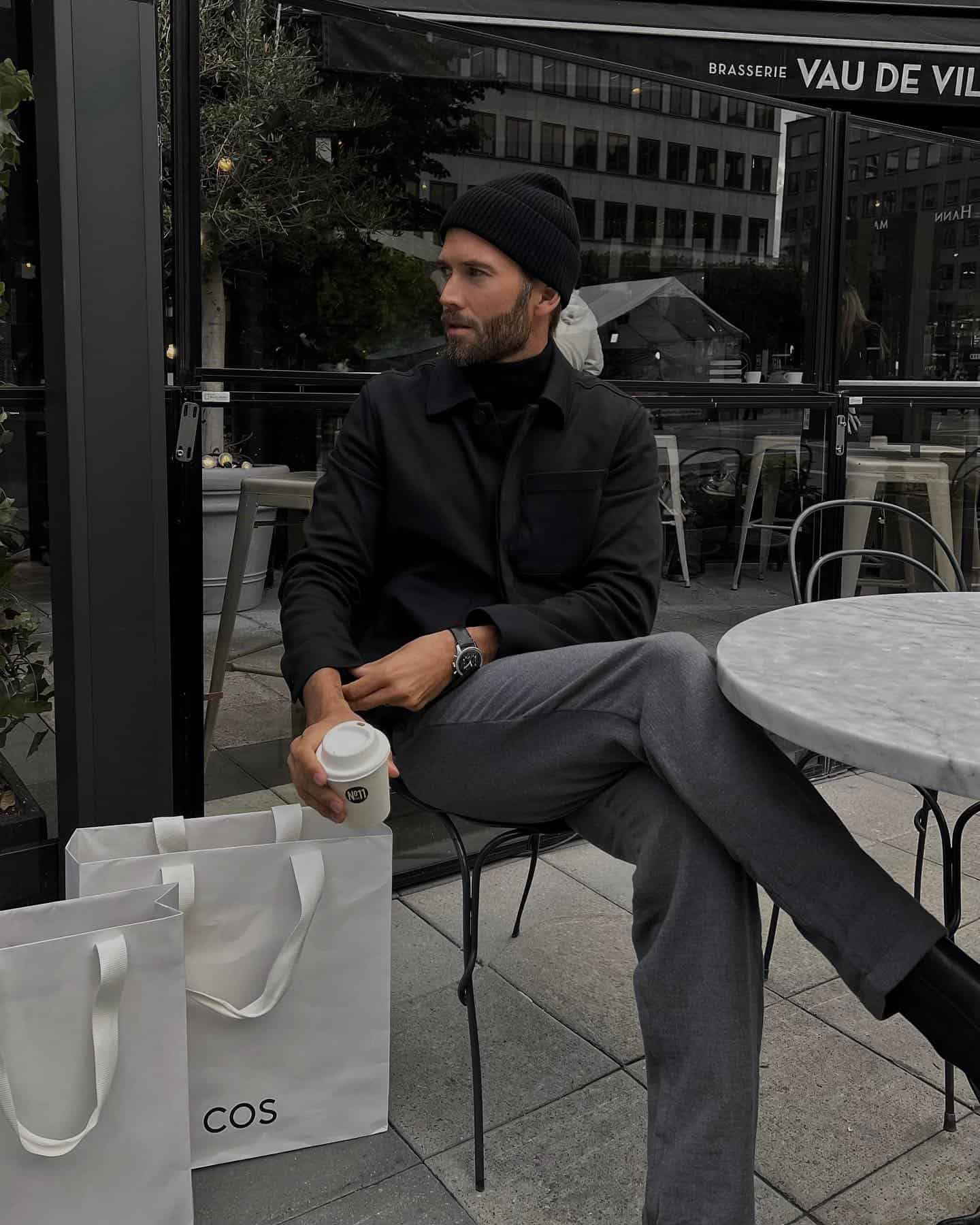 man sitting by the table holding a cup of coffee