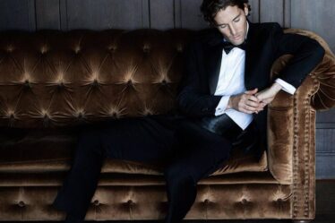 man in a tuxedo sitting on a couch