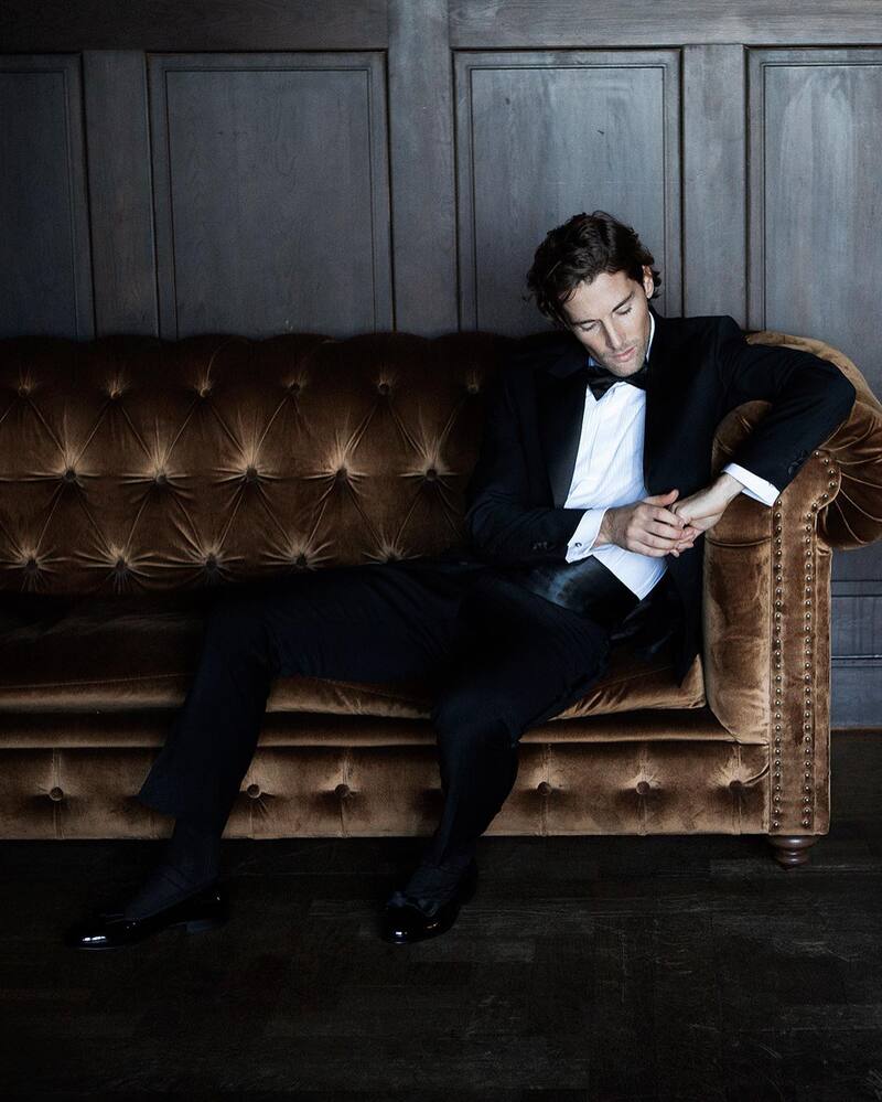 man in a tuxedo sitting on a couch