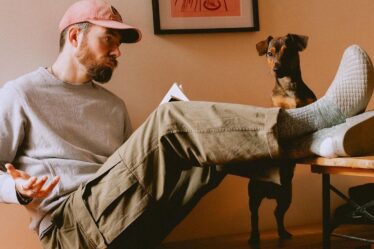 man sitting with his feet up on a desk looking at a dog