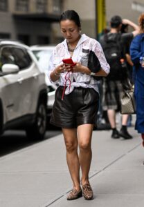 NEW YORK NEW YORK  SEPTEMBER 09 A guest is seen wearing a sheer white button down top black faux leather shorts and...