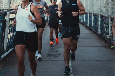 smiling group of young runners crossing a bridge