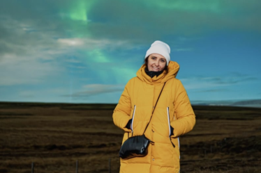 woman wears Orolay Thickened Long Down Jacket in Iceland while watching Northern Lights