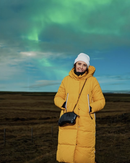 woman wears Orolay Thickened Long Down Jacket in Iceland while watching Northern Lights