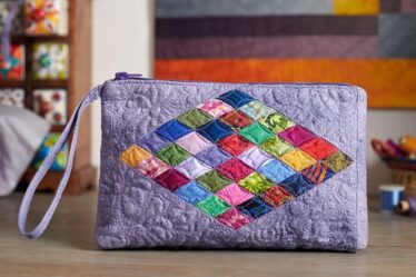 A colorful quilted handbag on a wooden surface