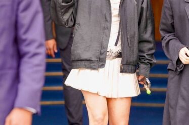 Rosalia wears a cream dress paired with a black bomber jacket and red knee-high boots as she greets fans outside a hotel in Paris.