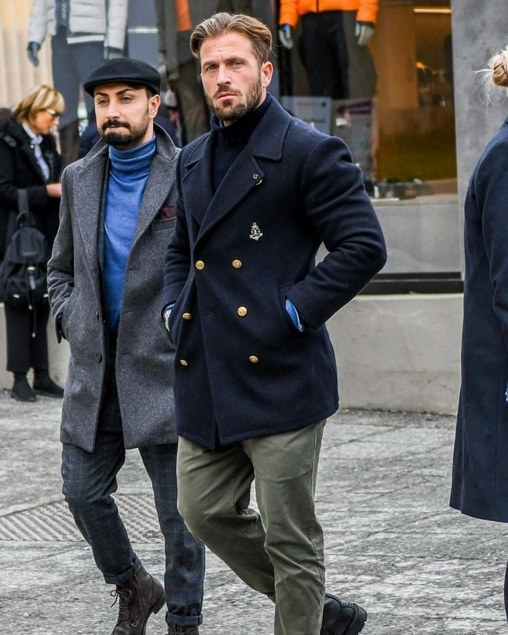 two men in coats walking with hands inside the pockets