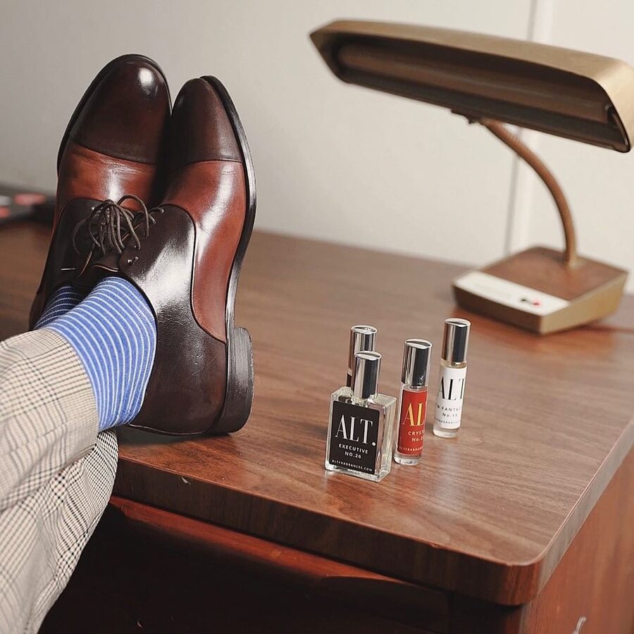 man resting feet on top of a table with a collection of alt fragrances colognes