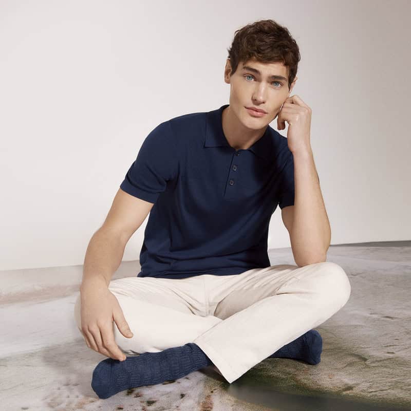 man sitting on the floor wearing navy polo shirt and white pants