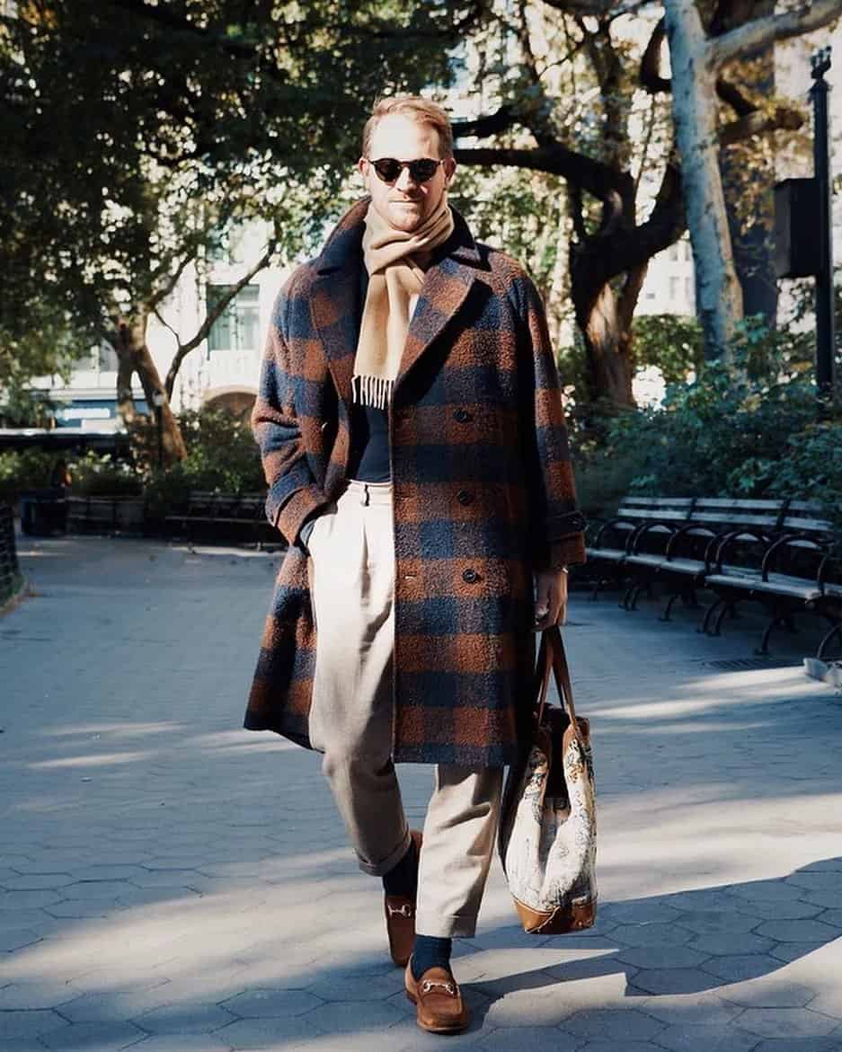 man in a long coat and carrying a tote bag