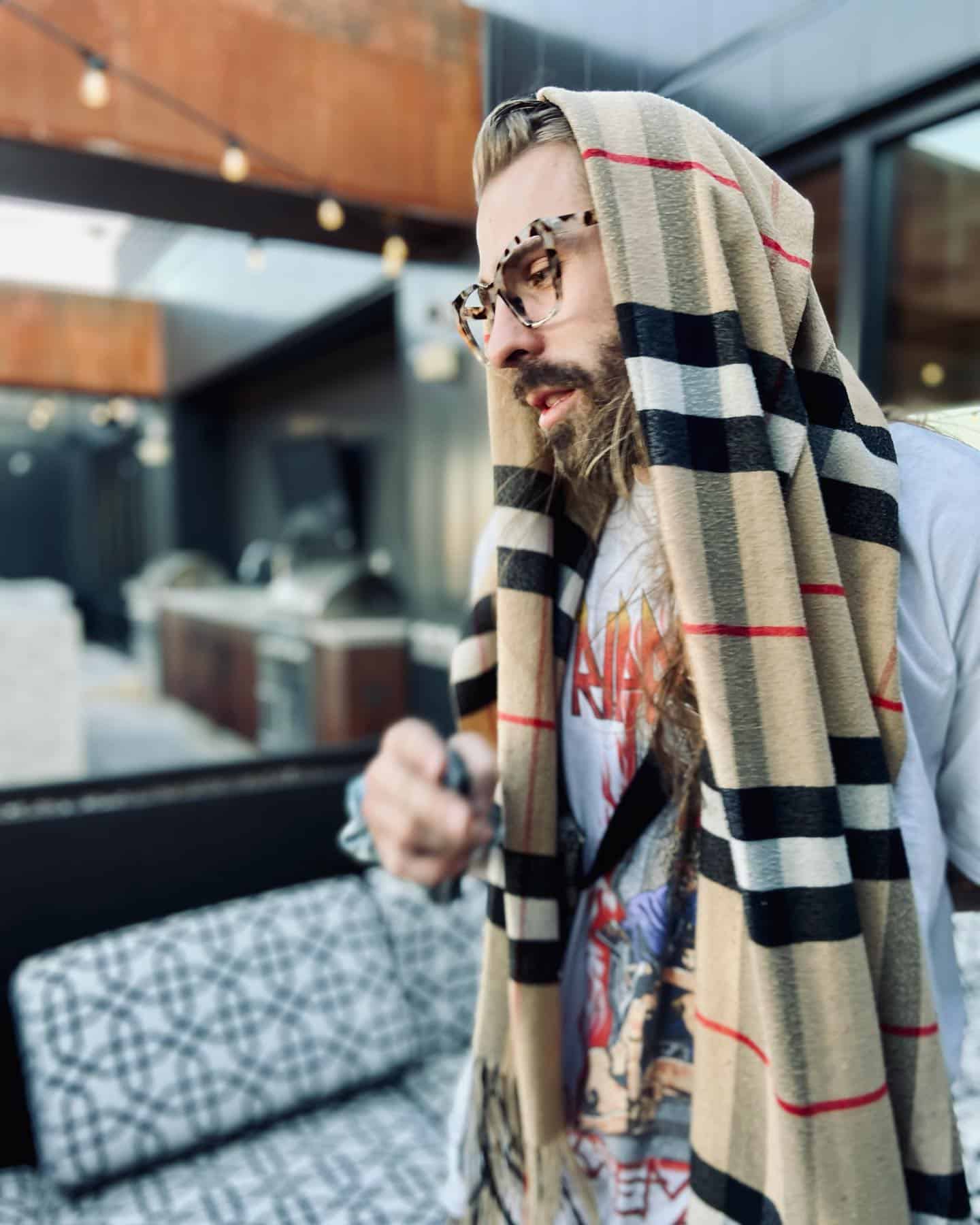 man covering head with a burberry checked scarf