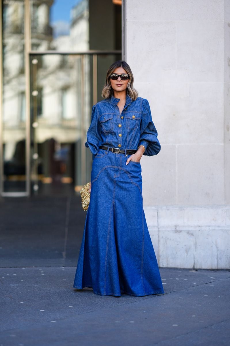 A guest wears a long blue denim dress, a black leather belt, a gold bag, sunglasses, outside Zimmermann, during the Womenswear Fall/Winter 2024/2025 as part of  Paris Fashion Week on March 04, 2024 in Paris, France. (Photo by Edward Berthelot/Getty Images)