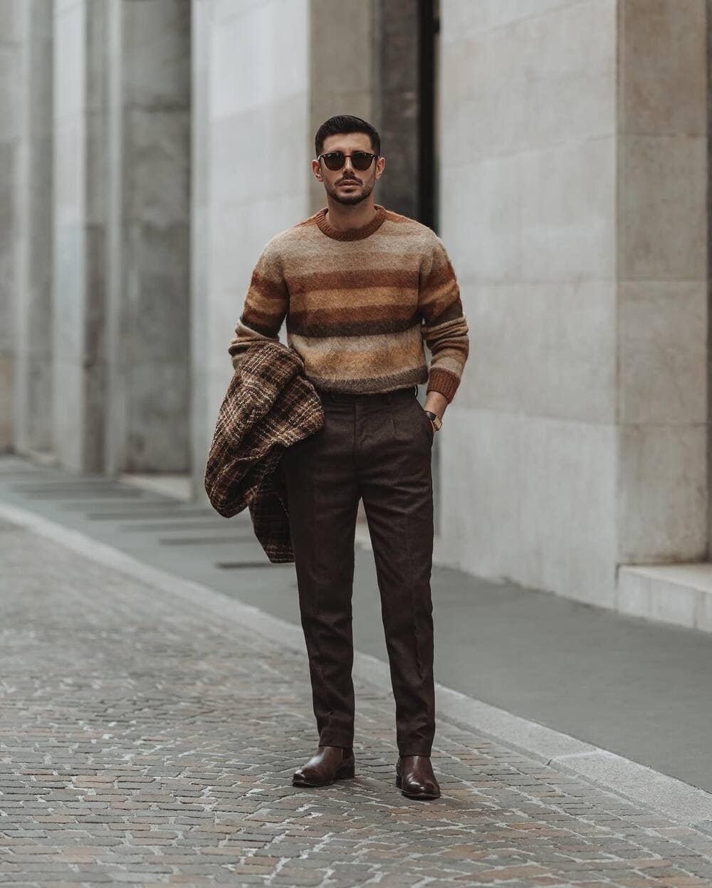 man wearing a sweater with shades of brown and a pair of brown pants