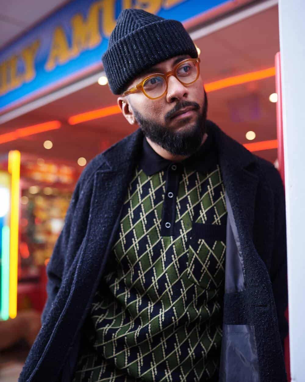 man with glasses wearing a wool overcoat and knitted beanie and shirt