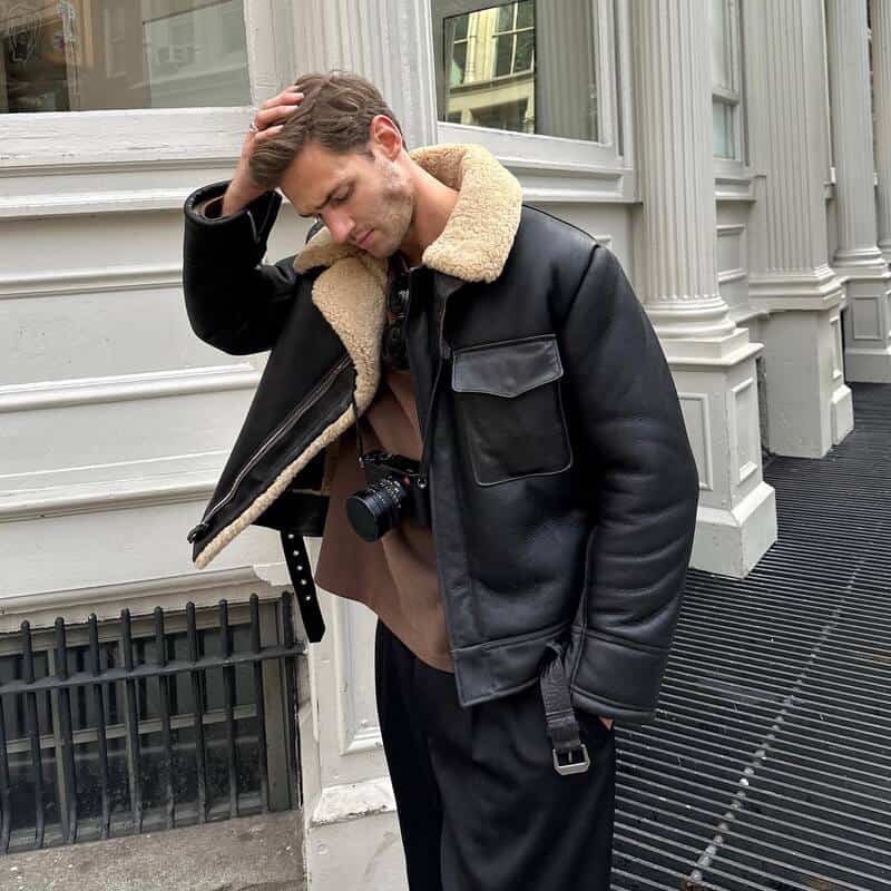 man wearing a shearling jacket with camera hanging on his neck