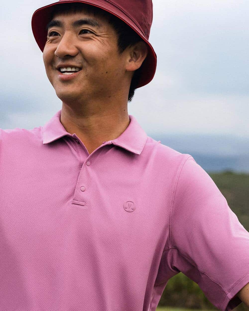 man wearing a pink polo shirt and maroon bucket hat