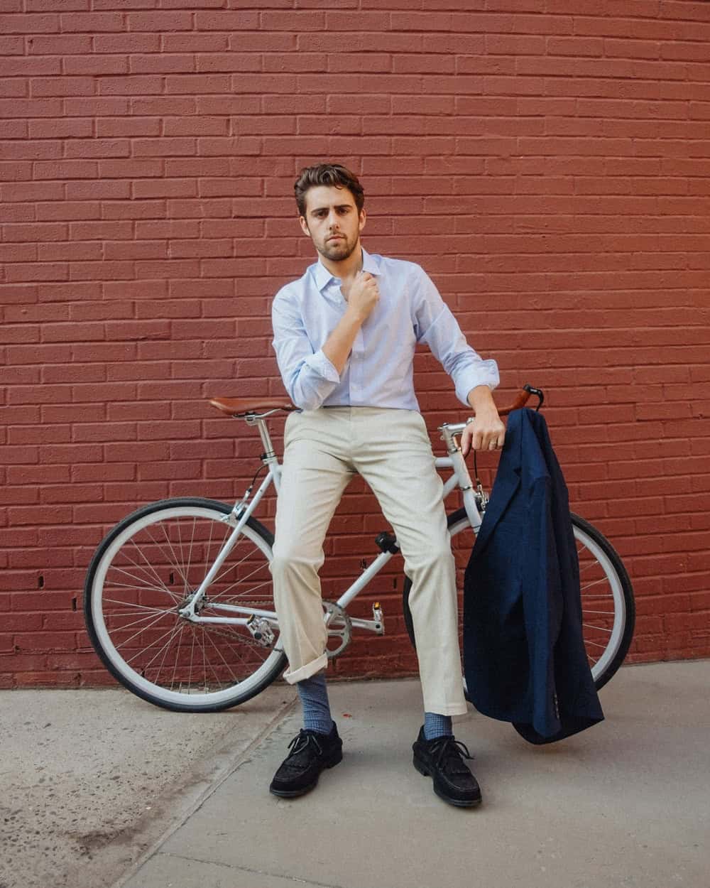 man in casual clothing sitting on the frame of a bicycle