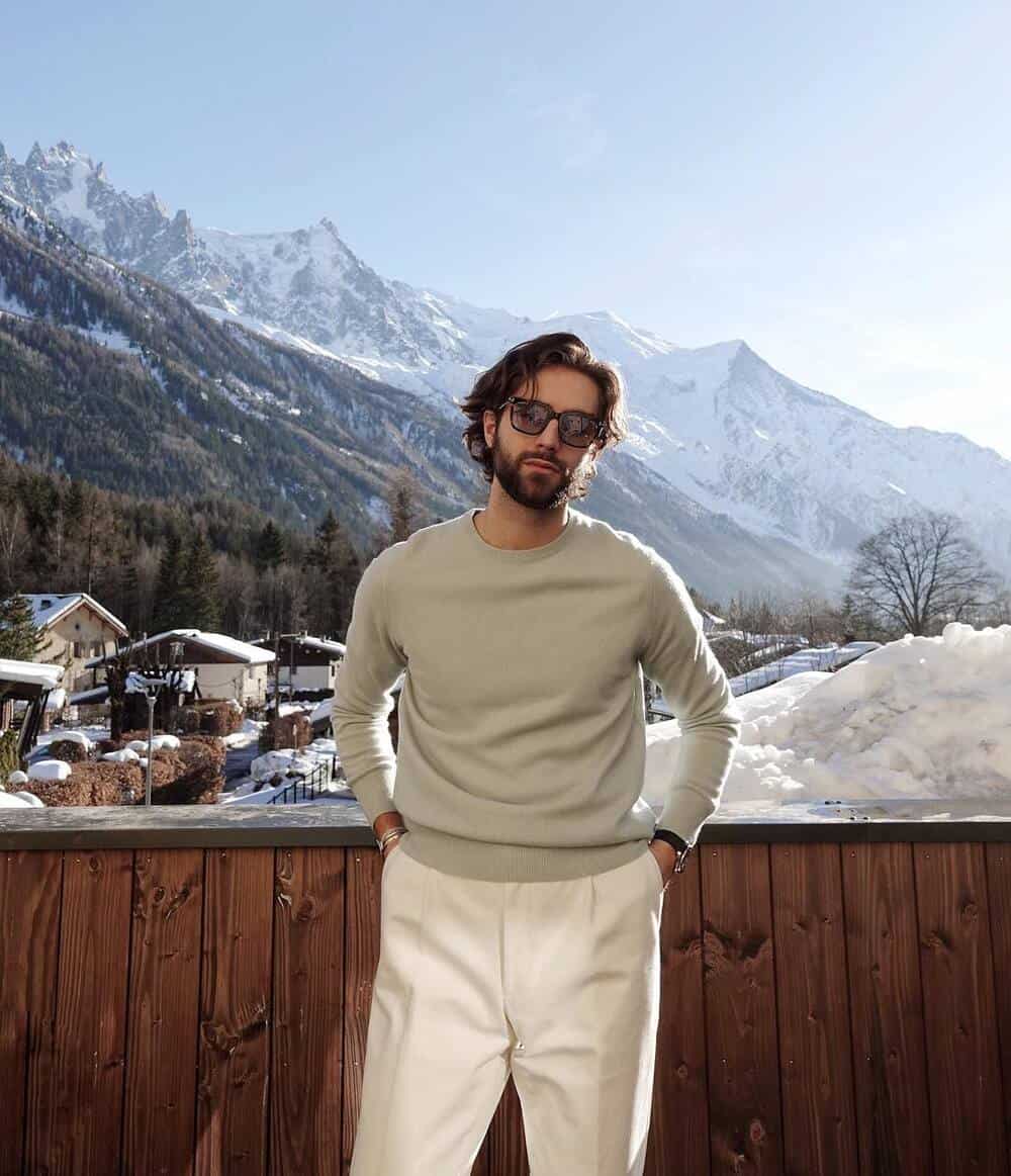 man with sunglasses wearing a crewneck sweater and white pants